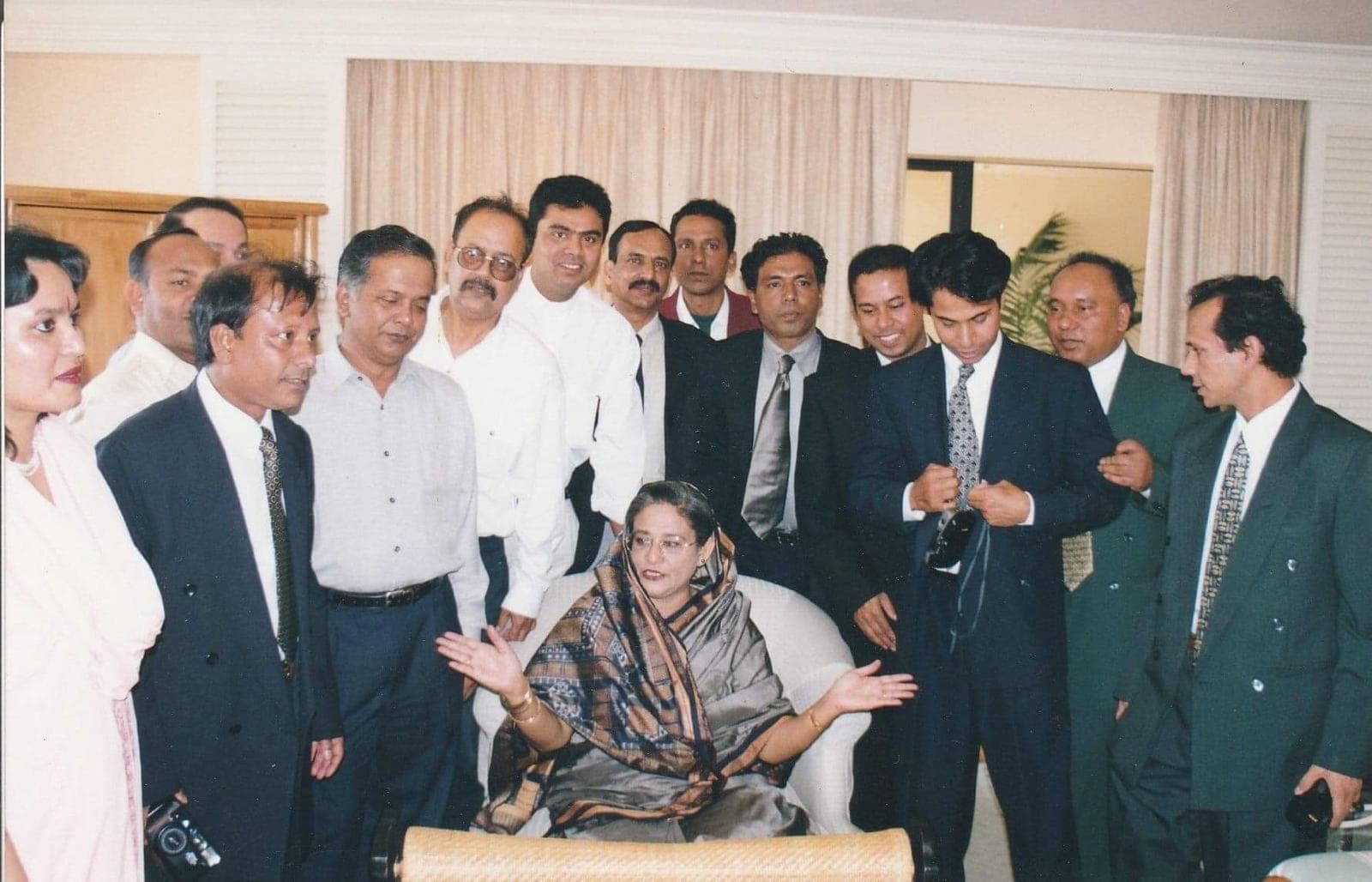 Sheikh Hasina sharing an interactive moment surrounded by community leaders and delegates in a formal setting